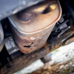 Widok od spodu na skorodowany tłumik Passata B6. Rdza przeżarła metal, tworząc dziury.