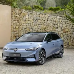 Niebieski Volkswagen ID.7, następca Passata, zaparkowany przed kamiennym murem.