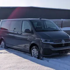 Szare auto 9 osobowe w zimowej scenerii, zaparkowane na śniegu.