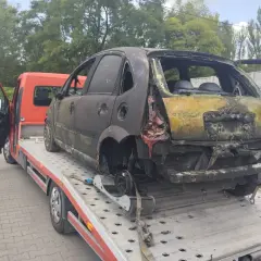 Spalony samochód na lawecie, gotowy do złomowania. Może to być początek drogi po dopłatę za złomowanie starego samochodu.