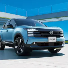 Niebieski Nissan Kicks, segment B, prezentuje się nowocześnie na tle betonowej konstrukcji i błękitnego nieba.