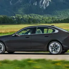 Ciemny sedan BMW jedzie przez malowniczy krajobraz. Idealny do biznesu, gdy rozważasz odliczenie VAT od leasingu samochodu osobowego powyżej 150 tys.