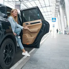 Kobieta wysiada z czarnego SUV-a. Zastanawia się, czy ubezpieczenie samochodu 75 czy 100 w koszty będzie lepsze.