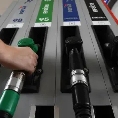 Ręka sięga po zieloną dyszę dystrybutora, obok czarne dysze do **diesel paliwo jak wygląda**.