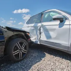 Zderzenie dwóch aut. Czarny samochód ma zniszczony przód, biały SUV wgniecione drzwi. Zastanawiasz się nad naprawa samochodu we własnym zakresie a odszkodowanie?