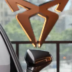 Biały samochód i logo producenta Cupra. Obok zdjęcie nowego modelu Cupra Leon PHEV.