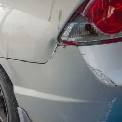 Uszkodzony tył samochodu po parkingowej stłuczce. Wgniecenie i liczne zarysowania lakieru, typowe dla szkody w leasingu.