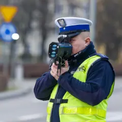 Policjant w kamizelce odblaskowej mierzy prędkość pojazdu. Uważaj na przekroczenie prędkości!