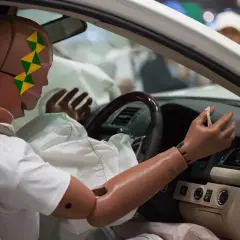 Manekin w samochodzie po teście zderzeniowym. Wystrzelone poduszki powietrzne otaczają manekina, budząc pytanie, czy wystrzelone poduszki dyskwalifikują auto.