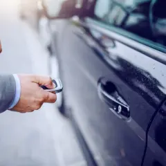 Biznesmen otwiera samochód kluczykiem. Zastanawiasz się, jak obliczyć amortyzację samochodu?