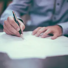Ręka pisze na papierze, analizując jak odliczyć leasing od podatku przykład.