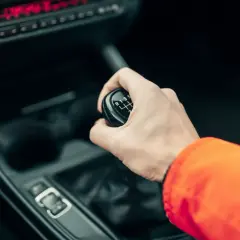 Dłoń zmienia biegi w manualnej skrzyni biegów w samochodzie.