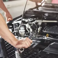 Mechanik z kluczami w dłoniach naprawia silnik samochodu. Bez ukrytej opłaty manipulacyjnej, tylko profesjonalna usługa.