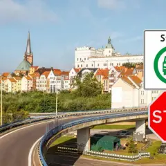 Znak "Strefa czystego transportu Szczecin" i czerwony znak STOP przed panoramą miasta.