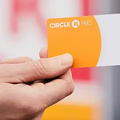 Dłoń trzyma pomarańczowo-białą kartę flotową Circle K PRO.