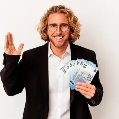Uśmiechnięty mężczyzna w garniturze trzyma banknoty 20 euro, symbolizujące łatwiejszą ratę kredytu samochodowego.