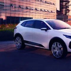 Nowy, biały izera samochód elektryczny na tle nowoczesnej architektury i zachodzącego słońca.