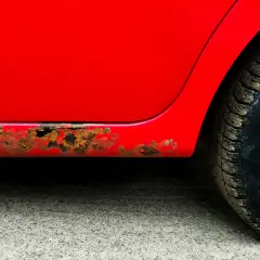 Rdza na samochodzie, widoczna na czerwonym progu, świadczy o jego wieku i trudach podróży.