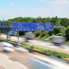 Autostrada w Niemczech, znaki drogowe wskazujące kierunki miast. Uważaj na odsetki za niezapłacony mandat w Niemczech, bo mogą Cię dogonić jak te ciężarówki.