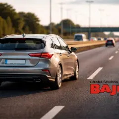 Szary samochód jedzie autostradą. Zastanawiasz się, ile można jechać poza terenem zabudowanym? Zapisz się na kurs do OSK BAJKA!
