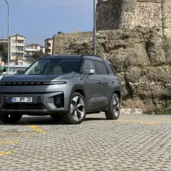Nowy SsangYong elektryczny SUV stoi na parkingu przed kamiennym murem.
