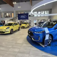 Salon Forda z kilkoma nowymi autami, w tym niebieskim SUV-em. Zastanawiasz się, auto w leasingu co to znaczy? To opcja dla Ciebie!