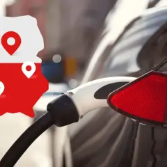 Mapa Polski z pinezkami wskazuje na punkty darmowe ładowanie elektryka. W tle widać ładowany samochód elektryczny.
