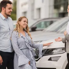 Para ogląda nowy samochód po leasingu, sprzedawczyni pokazuje mu detale.