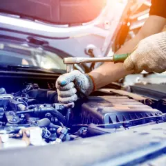 Mechanik dokręca śrubę w silniku. Silentblock to element amortyzujący drgania, kluczowy dla komfortu jazdy.