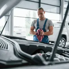 Mechanik w warsztacie z ręcznikiem w dłoniach. Zastanawiasz się, kto płaci VAT za naprawę samochodu w leasingu? Sprawdź szczegóły.