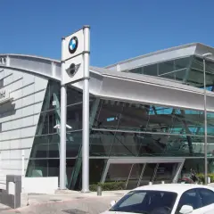 Nowoczesny salon MINI Madrid z logo BMW. W tle widać budynek i dźwig budowlany, a przed nim zaparkowane samochody, gotowe do akcje przywoławcze BMW.