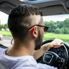 Mężczyzna w okularach przeciwsłonecznych prowadzi Audi. Zastanawia się, ile mam czasu na ubezpieczenie samochodu po zakupie, by móc legalnie jeździć.