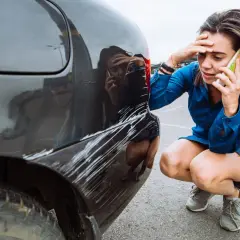 Zmartwiona kobieta dzwoni po pomoc po tym, jak jej auto w leasing ucierpiało w wyniku szkody z OC sprawcy.