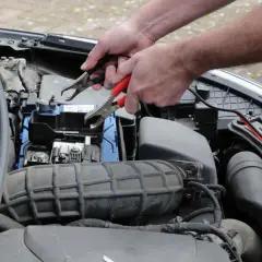 Ręce podłączają kable do akumulatora, by rozwiązać problem nagłego wzrostu spalania diesel.