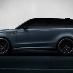 Elegancki, ciemnoszary land rover elektryczny z czarnymi felgami, poruszający się po ciemnej drodze.