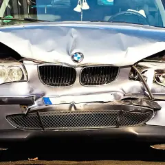 Uszkodzony BMW po wypadku. Zderzak, maska i reflektory są zniszczone. Wygląda na to, że czeka go szkoda całkowita, mimo że był w leasingu.