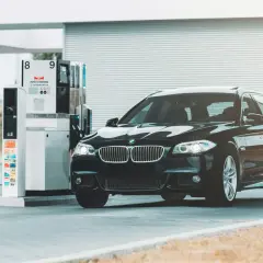 Czarne BMW na stacji paliw. Przykład, jak odliczyć 50% VAT od paliwa, może być związany z kosztami podróży służbowych.