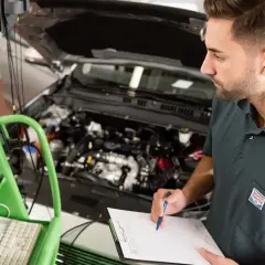 Mechanik sprawdza wyniki diagnostyki komputerowej podczas pierwszego przeglądu gwarancyjnego samochodu.