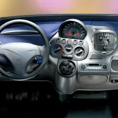 Widok na **fiat multipla wnętrze**: kierownica, deska rozdzielcza z radiem i nawiewami, dźwignia zmiany biegów.