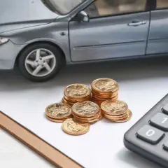 Model samochodu, stos monet i kalkulator. Obliczenia finansowe dla leasingu powyżej 150 tys. zł.