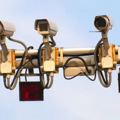 Trzy kamery monitorujące ruch drogowy, każda z migającym **system red light** pod nią.
