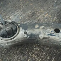 Metalowy pręt włożony w zniszczony gumowy element wahacza. To pokazuje, jak sprawdzić sworzeń wahacza.