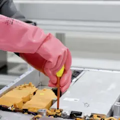 Ręce w różowych rękawicach dokręcają śrubę w pakiecie akumulatorów grafenowych.