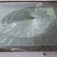 Pęknięta szyba w aucie, z pajęczyną pęknięć rozchodzących się od centralnego punktu.