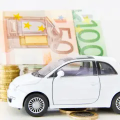 Biały samochodzik na monetach i banknotach euro. Zastanawiasz się, co z leasingiem po zamknięciu firmy?