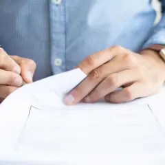 Mężczyzna w niebieskiej koszuli podpisuje dokument. Czy to weksel? Co to jest weksel?