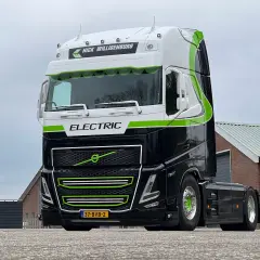 Nowoczesna, czarna elektryczna ciężarówka z zielonymi akcentami i napisem "ELECTRIC" gotowa do drogi.