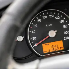Zbliżenie na deskę rozdzielczą samochodu. Widoczny prędkościomierz, wskaźnik paliwa i temperatury. Cyfrowy wyświetlacz pokazuje przebieg 216621 km.