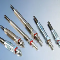 Kilka świec żarowych ułożonych na metalicznej powierzchni. Zepsute świece żarowe objawy mogą być trudne do zauważenia.