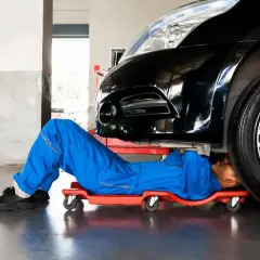 Mechanik pod czarnym autem szuka czujnika położenia wału w Peugeot 207.